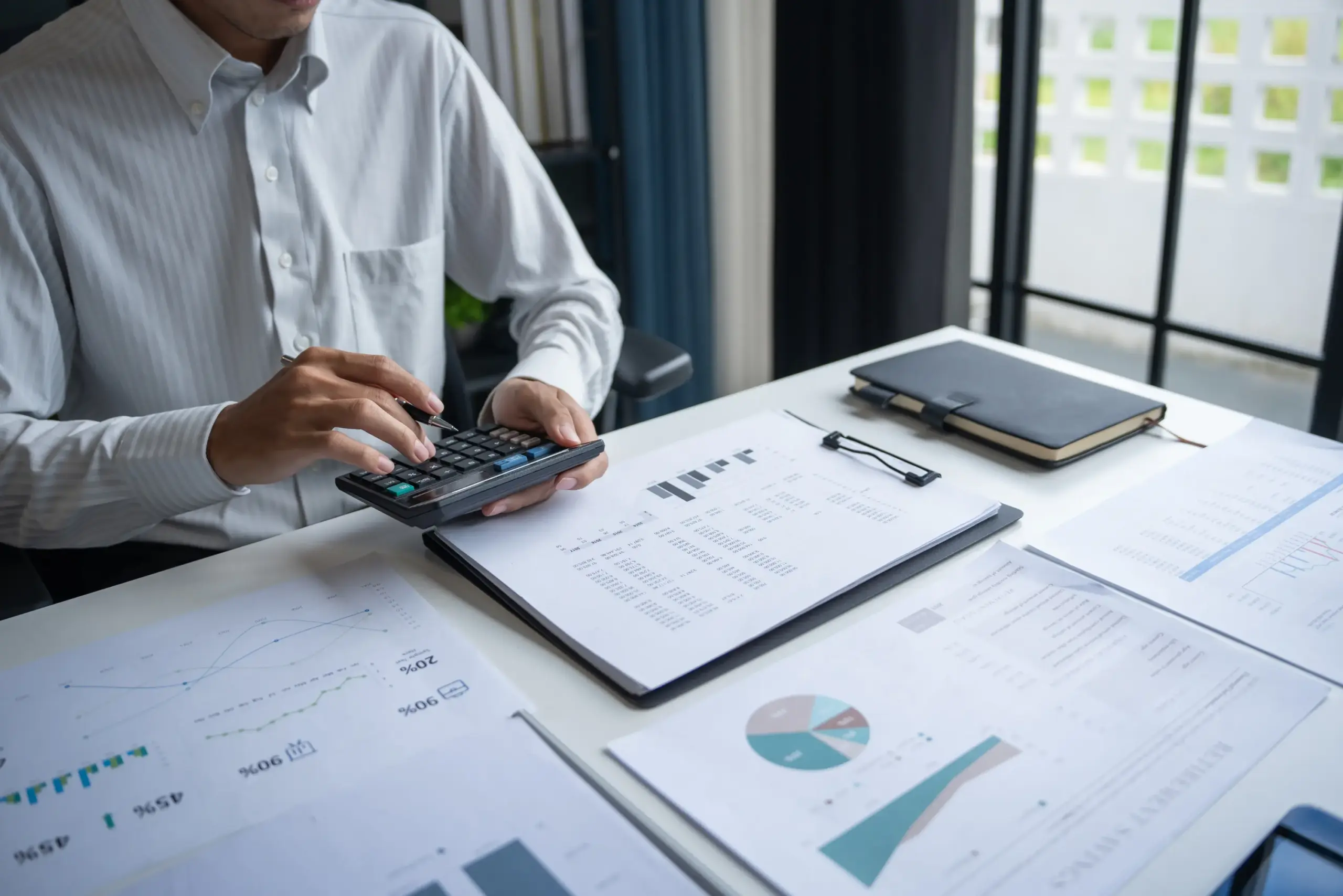 Person using a calculator while reviewing financial documents and charts