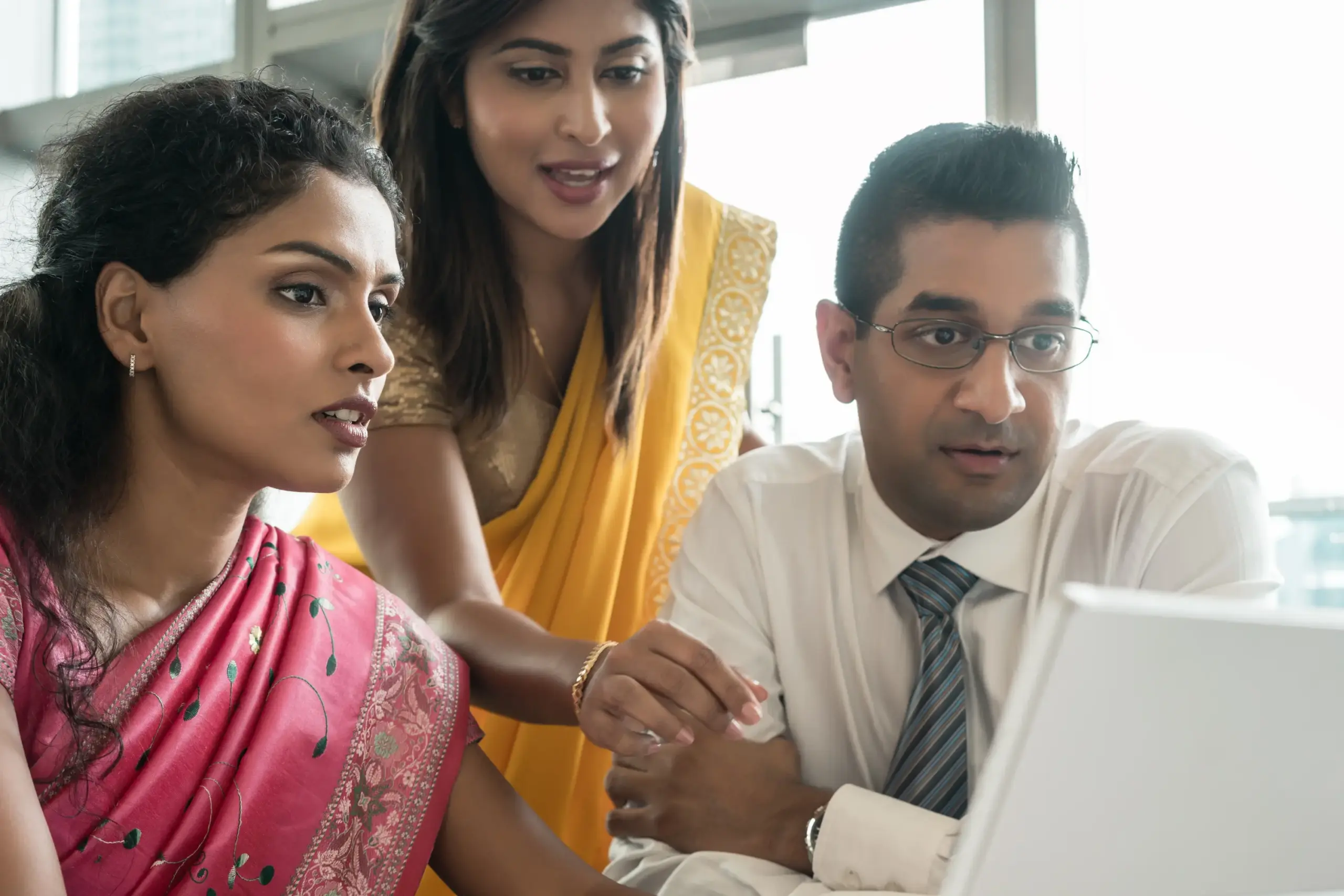 Financial advisors reviewing documents and data on a laptop